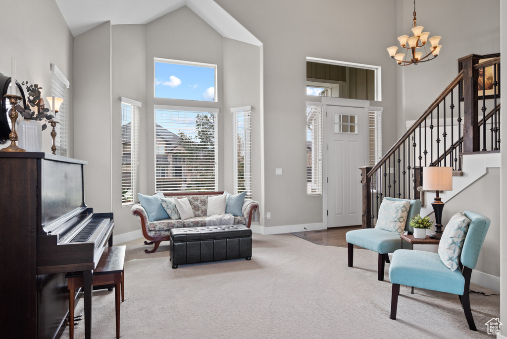 Living area with a chandelier, baseboards, and high vaulted ceiling