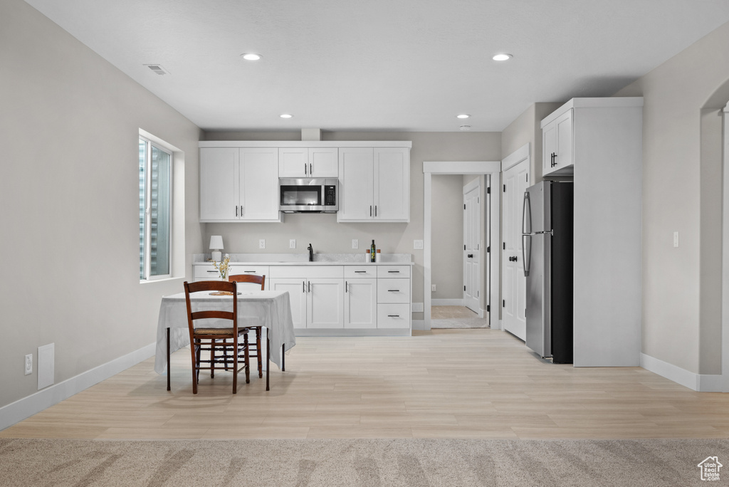 Kitchen with stainless steel appliances, baseboards, and white cabinets