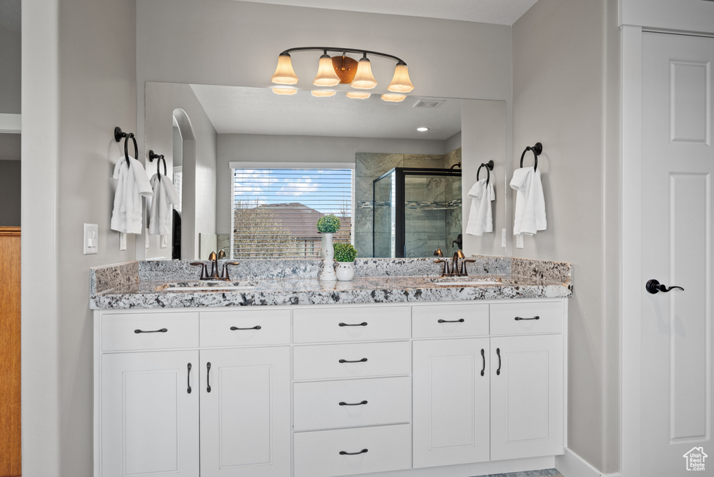 Full bathroom featuring a sink, double vanity, and a shower stall