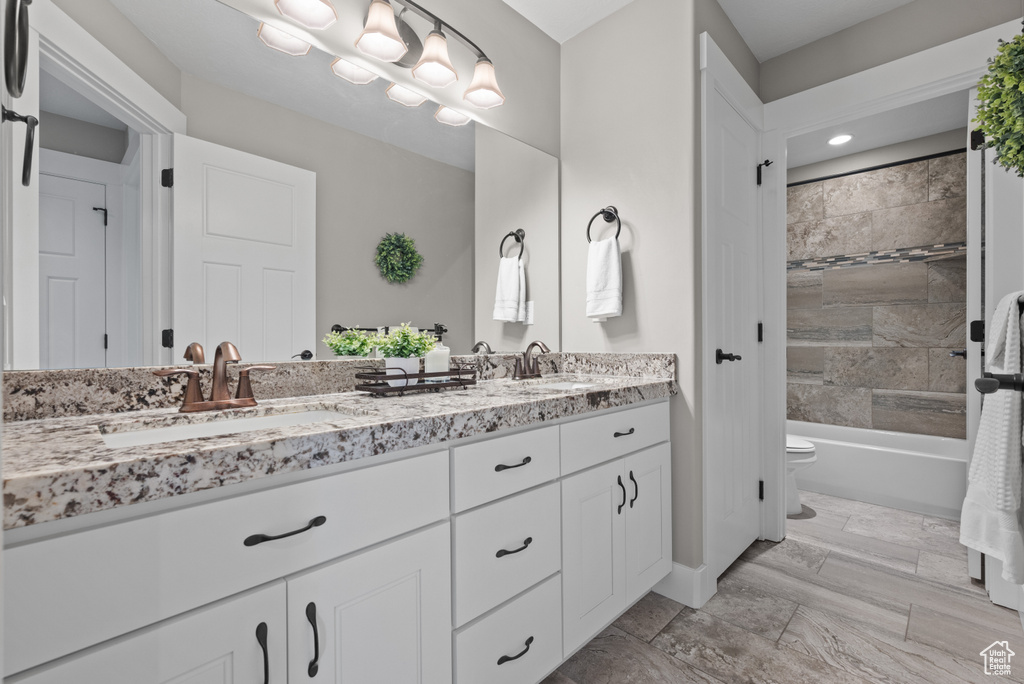 Full bath with a sink, double vanity, toilet, and tub / shower combination