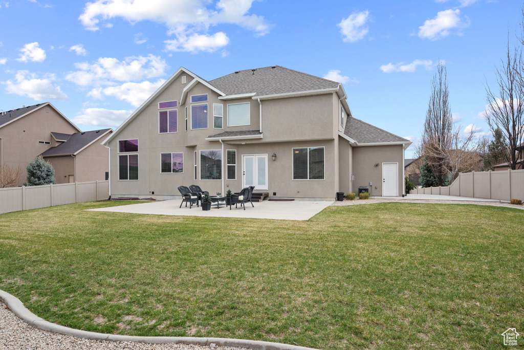 Back of house with a lawn, a patio, stucco siding, and a fenced backyard