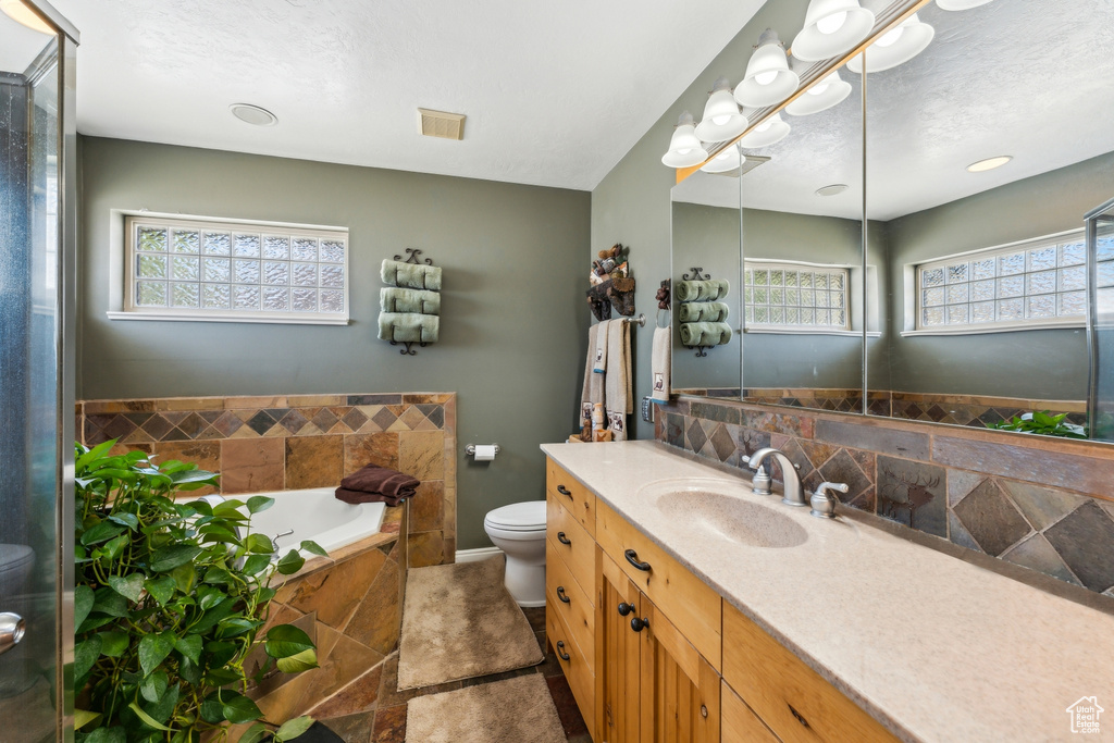 Bathroom featuring toilet, vanity, a bath, and baseboards
