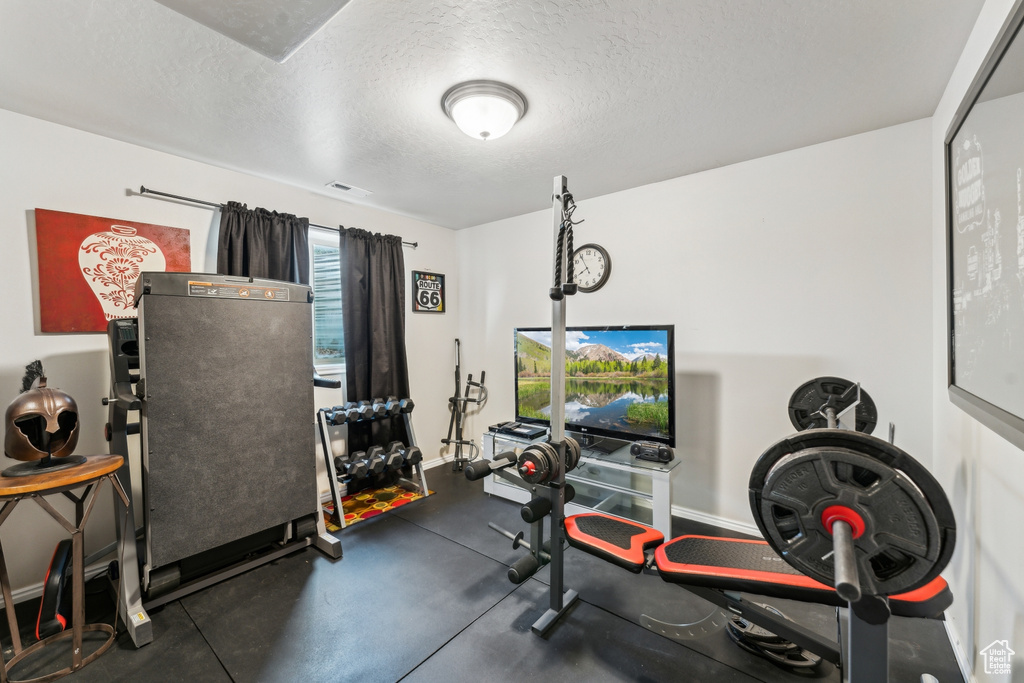 Workout area with a textured ceiling and baseboards