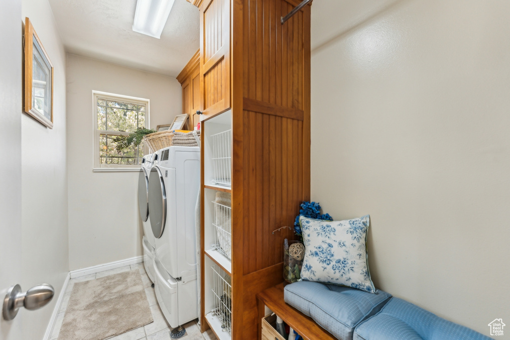 Laundry room featuring independent washer and dryer, cabinet space, baseboards, and light tile patterned floors