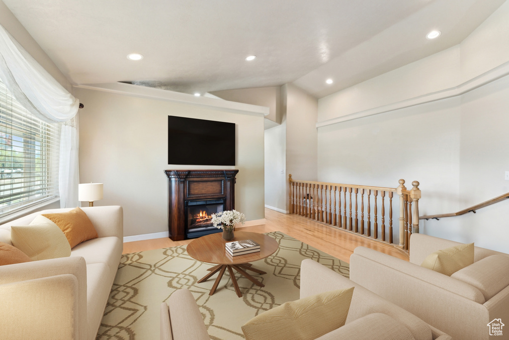 Living area featuring recessed lighting, light wood-style floors, baseboards, a lit fireplace, and lofted ceiling
