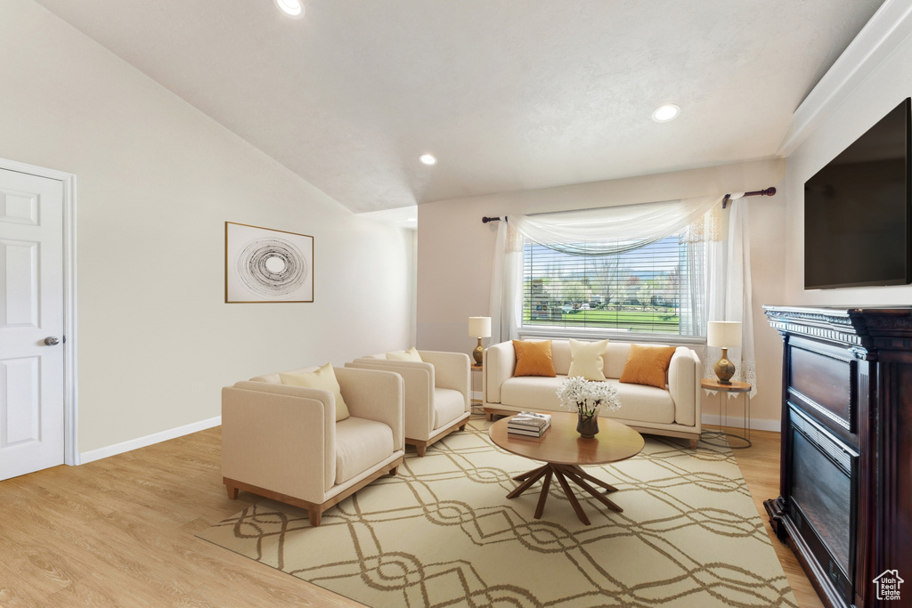 Living area featuring a glass covered fireplace, wood finished floors, recessed lighting, vaulted ceiling, and baseboards