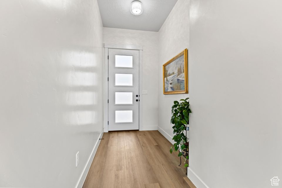 Doorway to outside featuring baseboards and light wood-style flooring