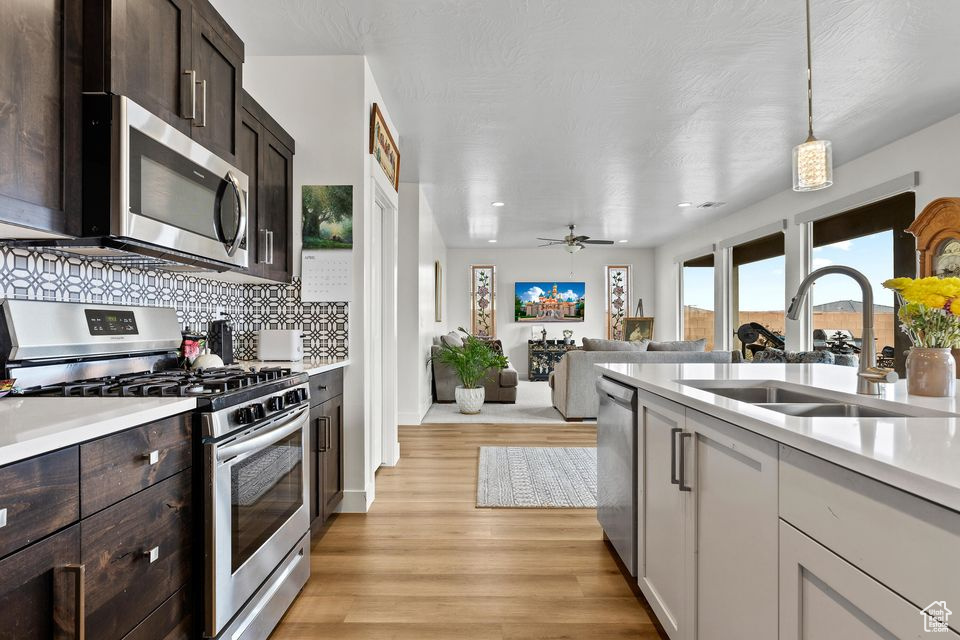 Kitchen with stainless steel appliances, light countertops, a sink, light wood-style flooring, and recessed lighting