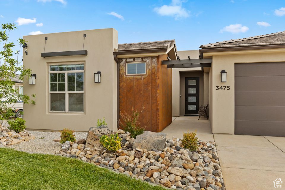 View of front facade featuring stucco siding, a garage, driveway, and a tile roof