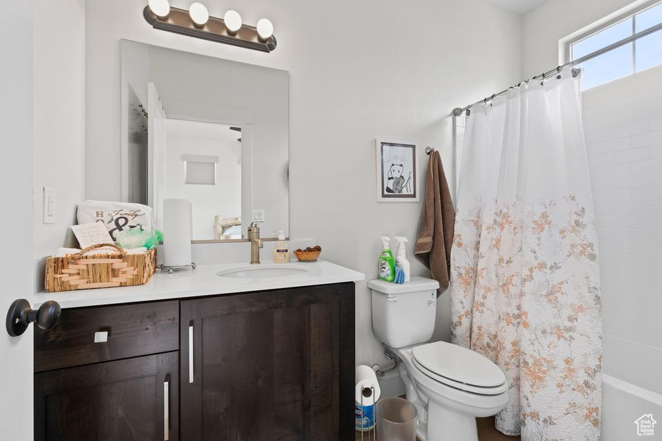Full bathroom with toilet, vanity, and shower / bath combo