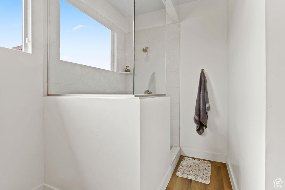 Bathroom featuring walk in shower, wood finished floors, and baseboards