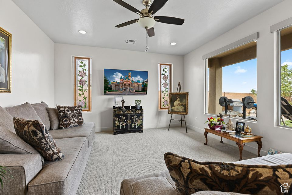 Carpeted living room featuring ceiling fan, baseboards, and recessed lighting