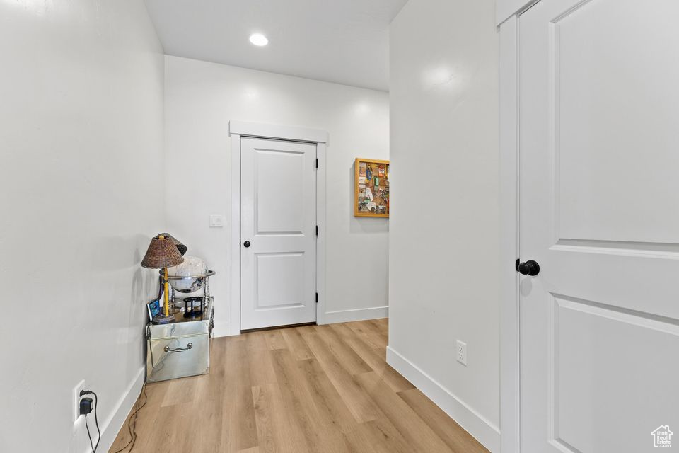Hallway with baseboards, light wood finished floors, and recessed lighting