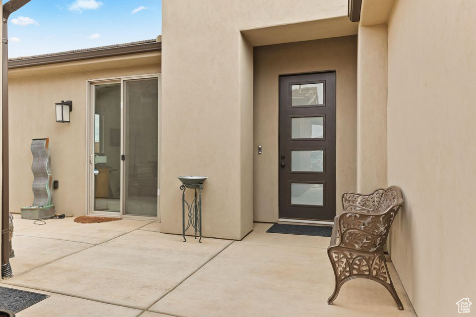 View of exterior entry with stucco siding and a patio area