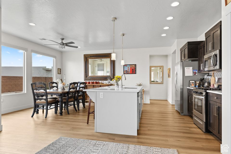 Kitchen featuring appliances with stainless steel finishes, light countertops, a kitchen island with sink, light wood-type flooring, and recessed lighting
