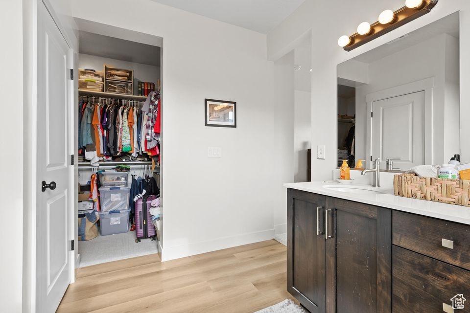 Bathroom featuring a spacious closet, wood finished floors, vanity, and baseboards