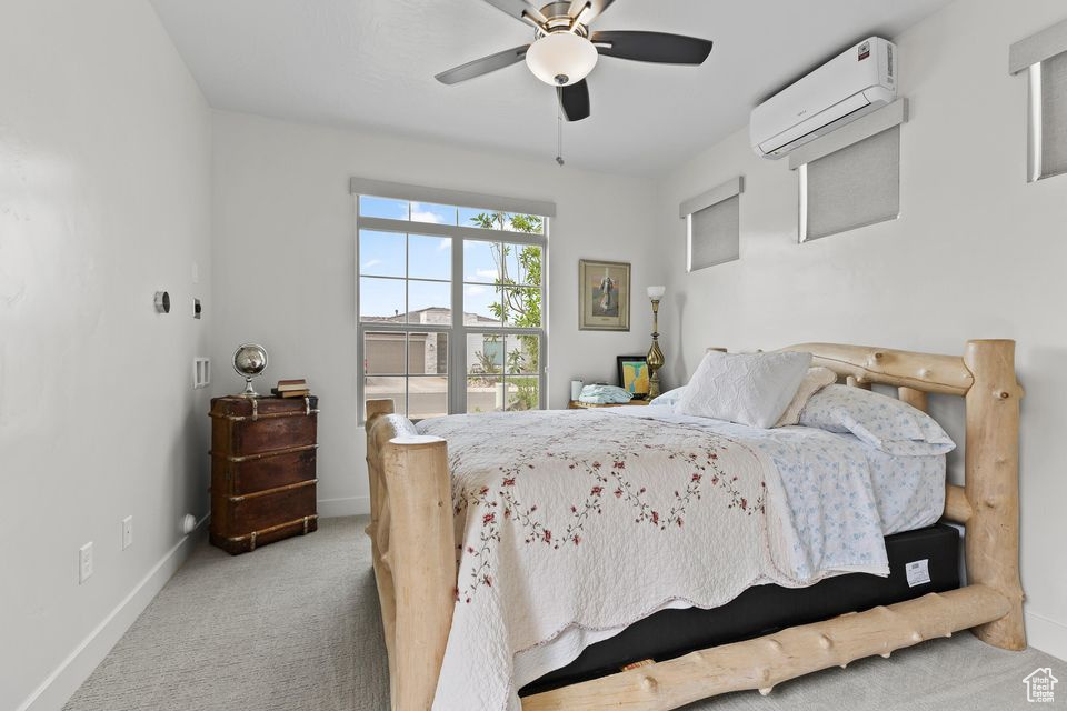 Bedroom featuring a wall mounted AC, carpet flooring, baseboards, and a ceiling fan