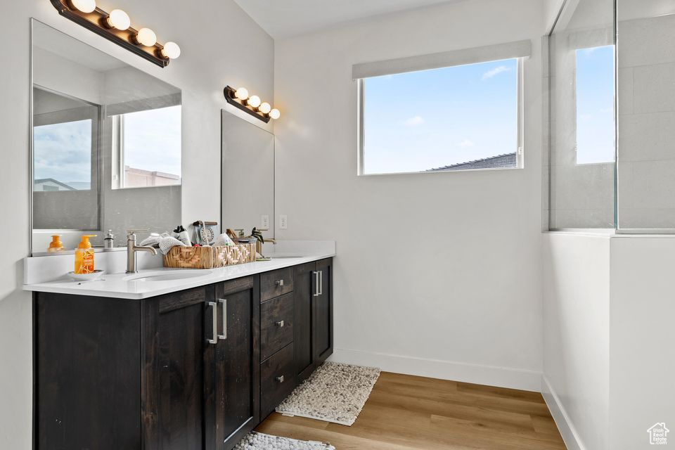 Bathroom with plenty of natural light, wood finished floors, baseboards, and double vanity