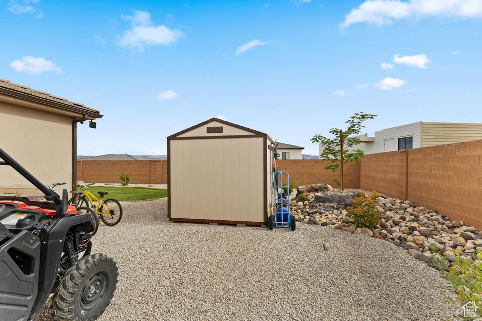 Fenced backyard featuring a storage shed and an outdoor structure
