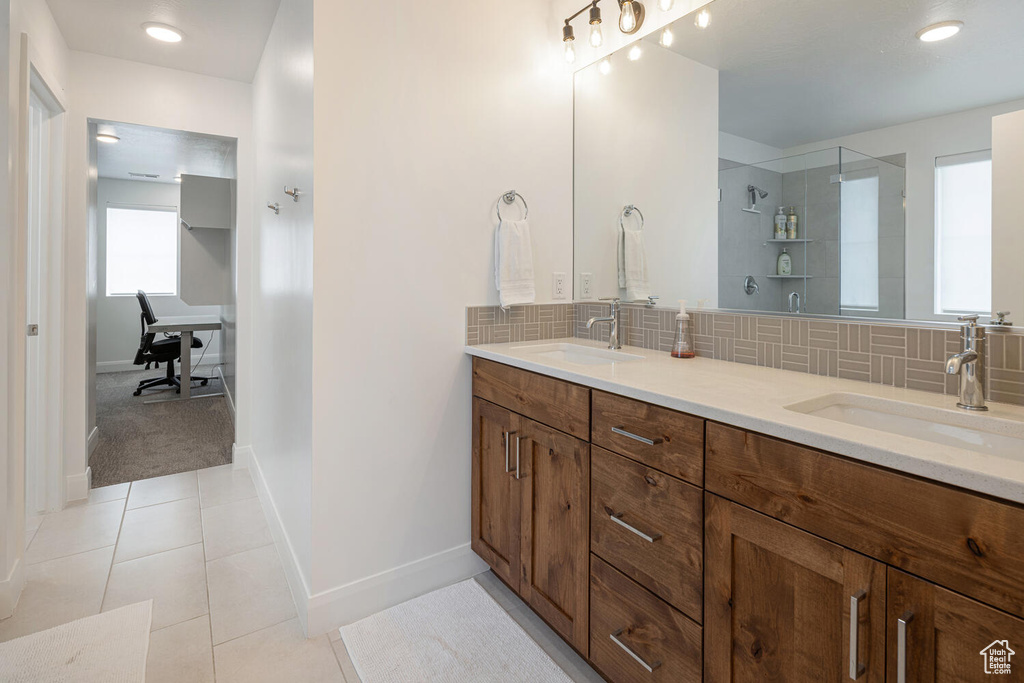 Full bathroom with a sink, double vanity, backsplash, and tiled shower
