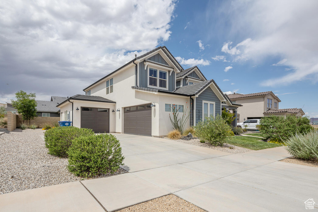Traditional-style home featuring stucco siding, driveway, fence, and a garage