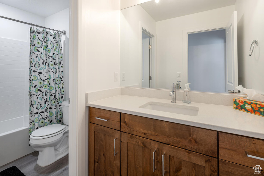 Full bath featuring vanity, toilet, shower / bathtub combination with curtain, and wood finished floors