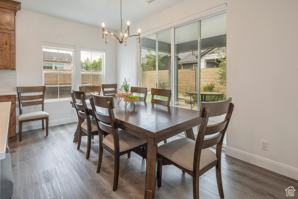 Dining area with a chandelier, wood finished floors, and baseboards