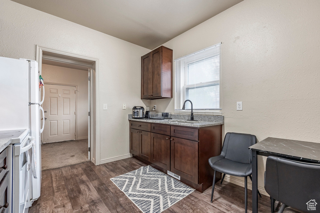 Kitchen featuring a sink, dark brown cabinetry, dark wood-style flooring, electric stove, and light stone counters