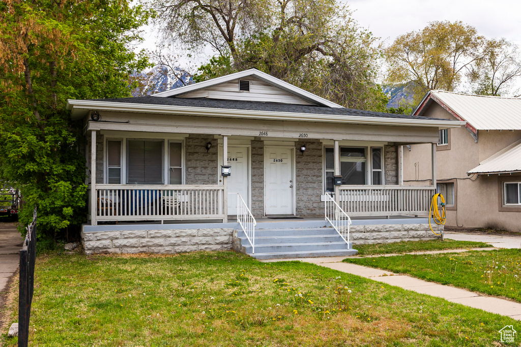 Bungalow-style house with covered porch, stucco siding, and a front lawn