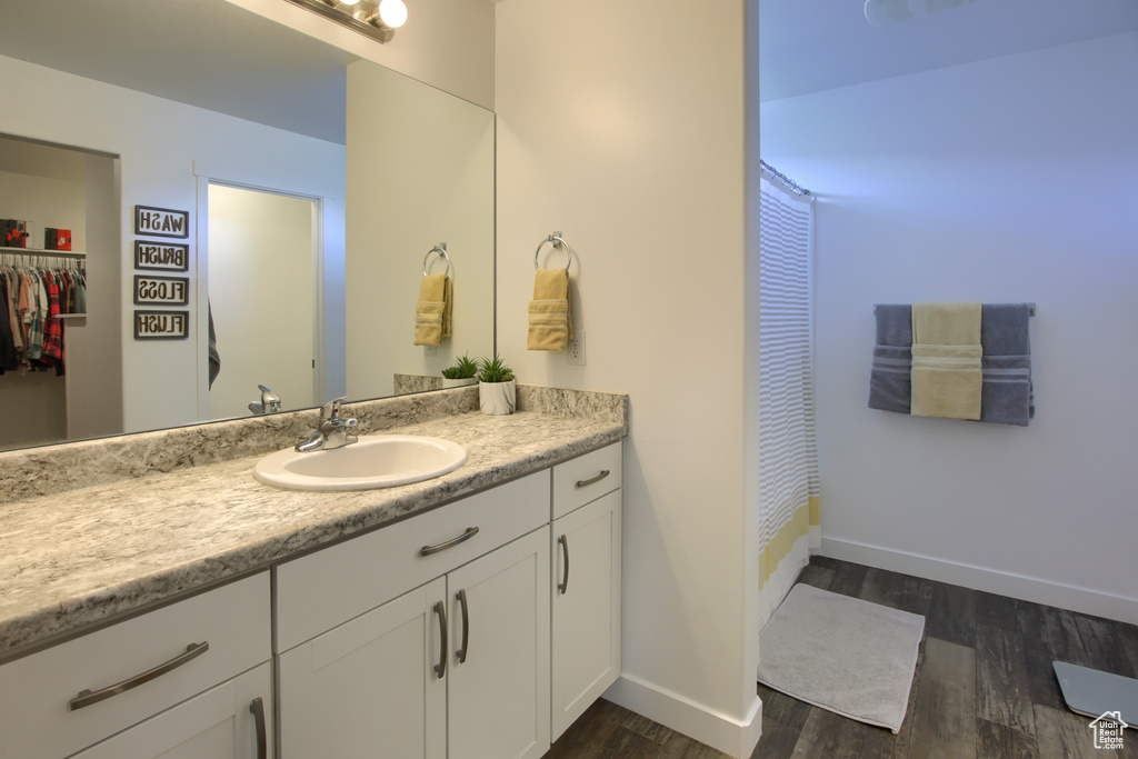 Full bath with vanity, baseboards, a shower with shower curtain, and wood finished floors
