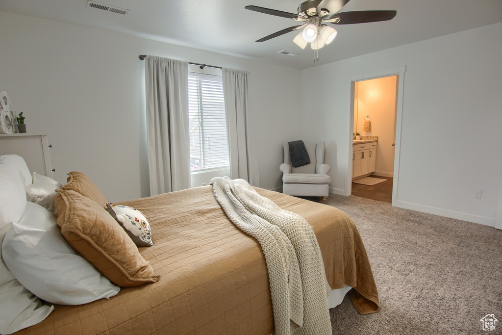 Carpeted bedroom featuring visible vents, a ceiling fan, baseboards, and ensuite bath