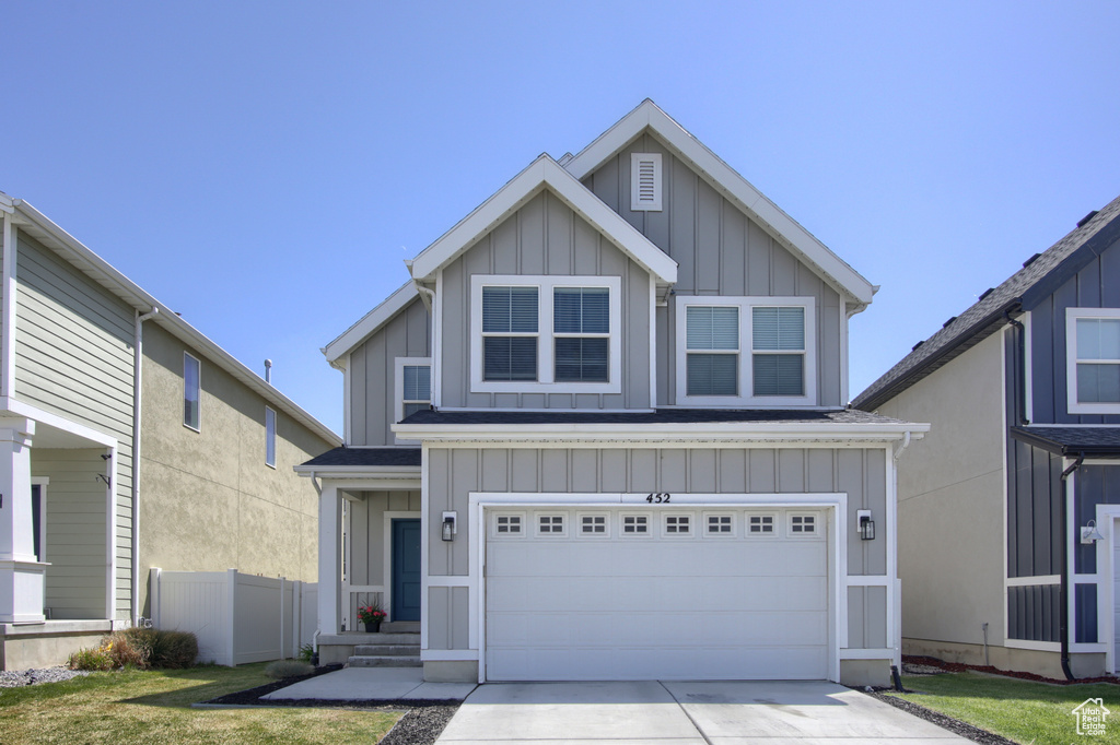 Craftsman-style house featuring a garage, board and batten siding, driveway, and a front lawn