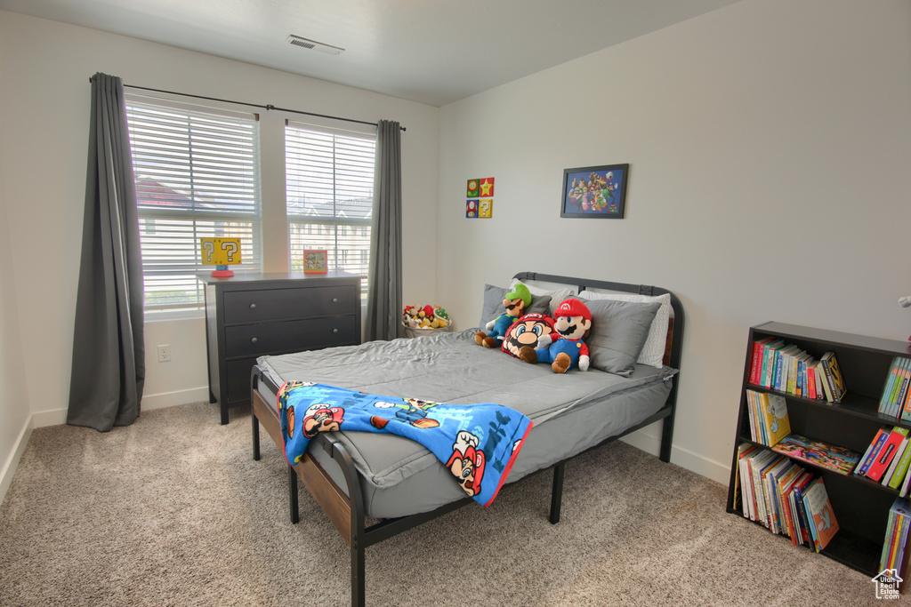 Bedroom with light colored carpet, baseboards, and visible vents