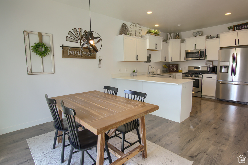 Kitchen featuring dark wood-style flooring, appliances with stainless steel finishes, a sink, and a peninsula