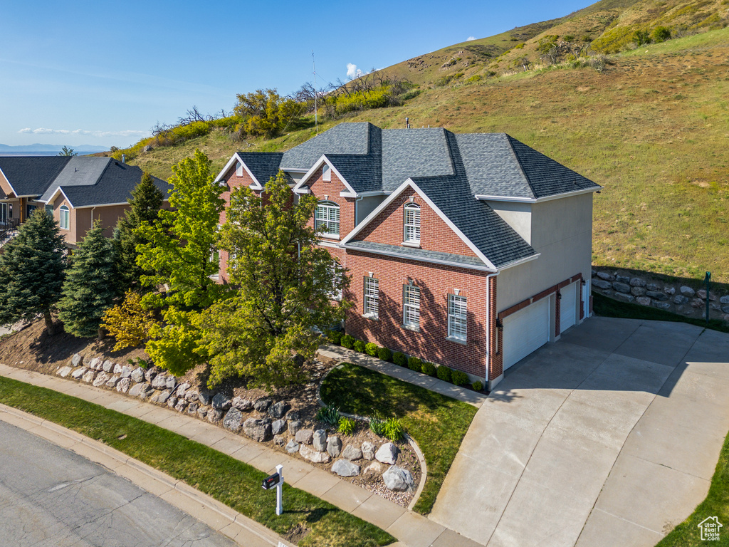 View of front of house featuring brick siding, a garage, roof with shingles, and concrete driveway