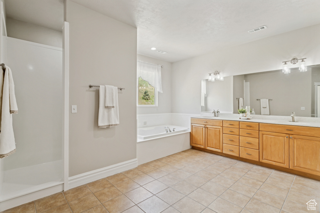 Full bathroom with visible vents, double vanity, a bath, tile patterned floors, and a sink