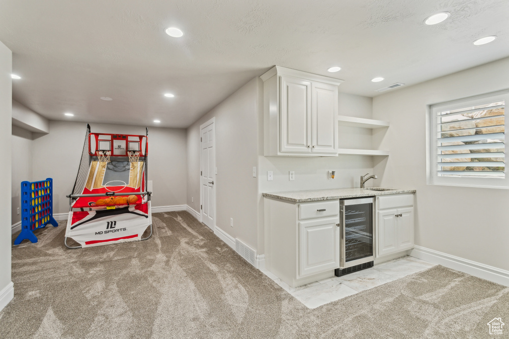 Bar with wine cooler, indoor wet bar, baseboards, recessed lighting, and a sink