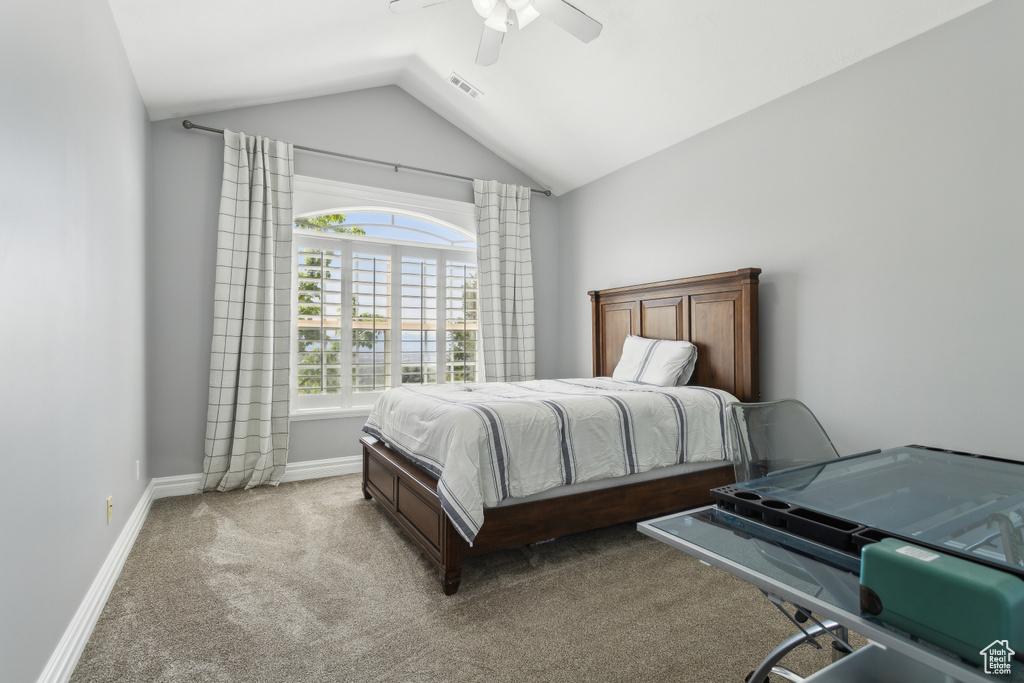 Carpeted bedroom with a ceiling fan, baseboards, visible vents, and lofted ceiling