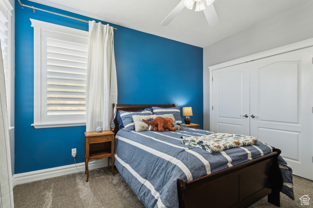 Carpeted bedroom with baseboards, ceiling fan, and a closet