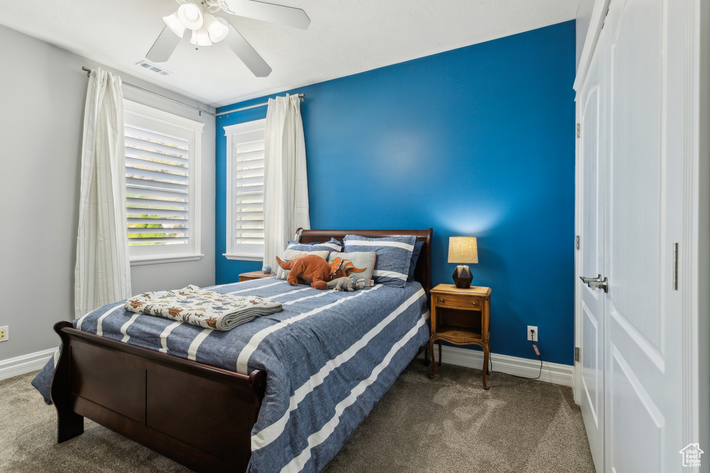Carpeted bedroom featuring visible vents, a ceiling fan, and baseboards