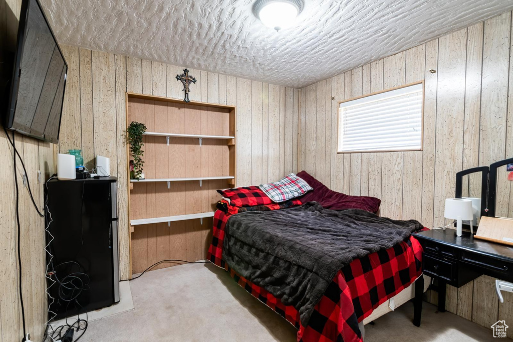 Carpeted bedroom featuring a textured ceiling and wooden walls
