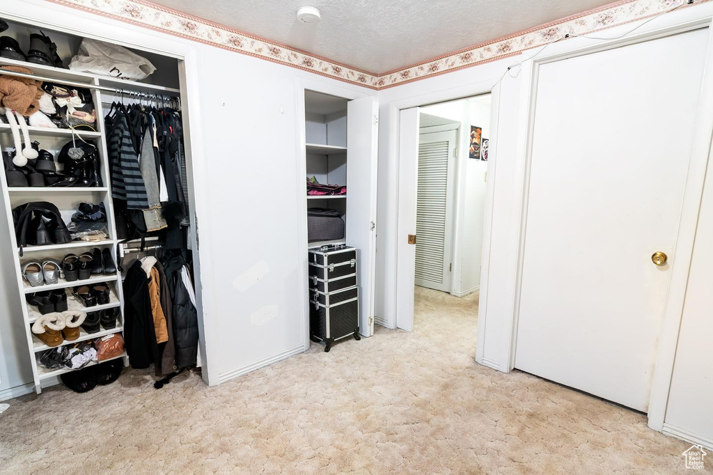 Bedroom featuring light carpet and multiple closets