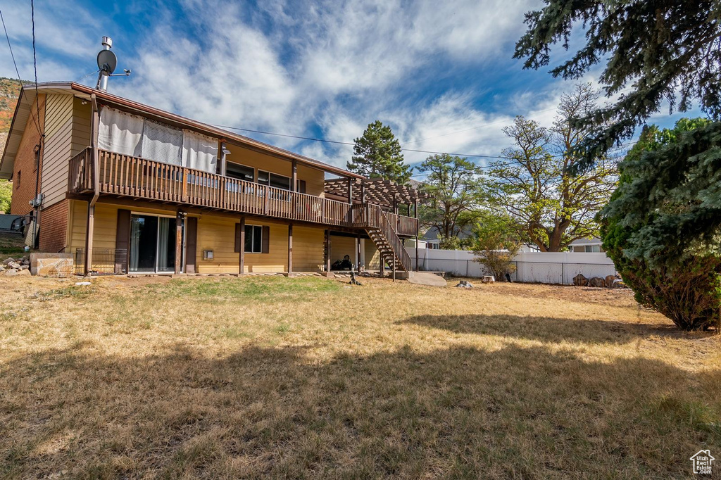 Rear view of house with a lawn, stairs, a deck, and fence
