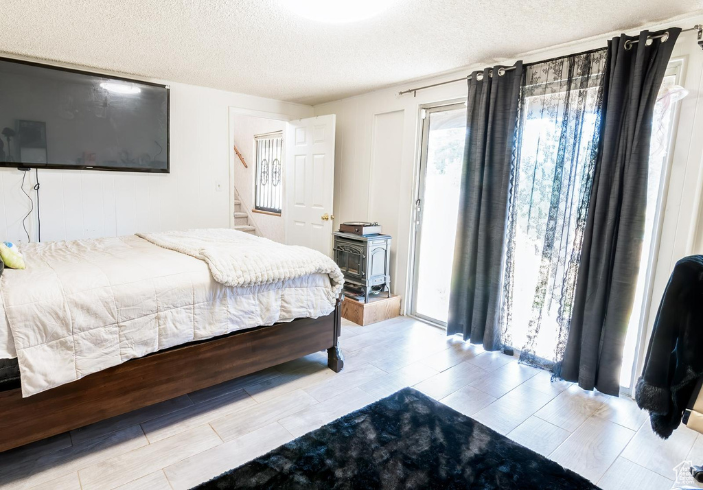 Bedroom with wood finish floors, access to outside, and a textured ceiling