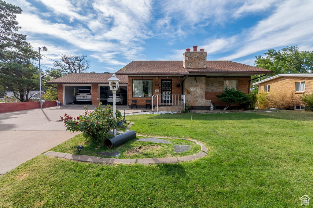View of front of home featuring covered porch, concrete driveway, a front lawn, and a chimney