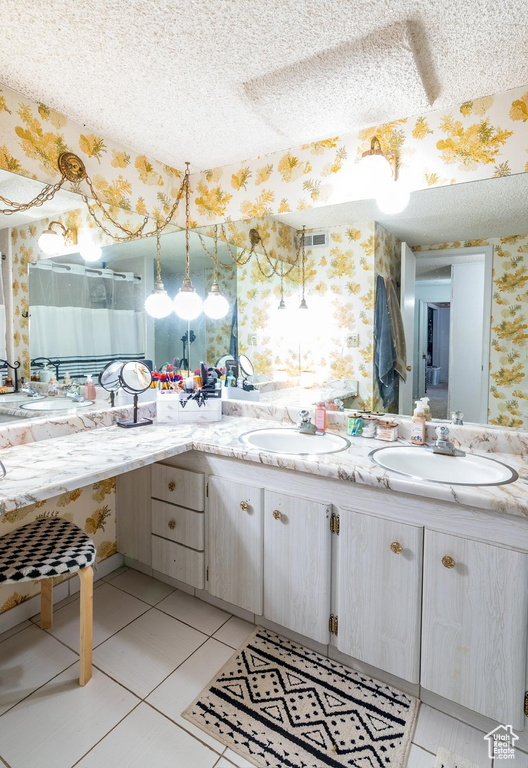 Bathroom featuring a sink, double vanity, wallpapered walls, and visible vents