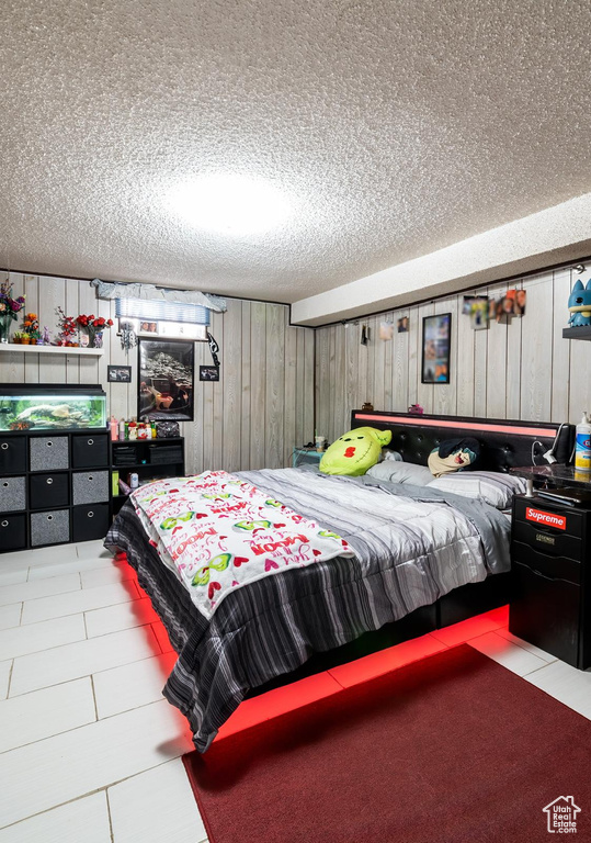 Bedroom with a textured ceiling and wood walls