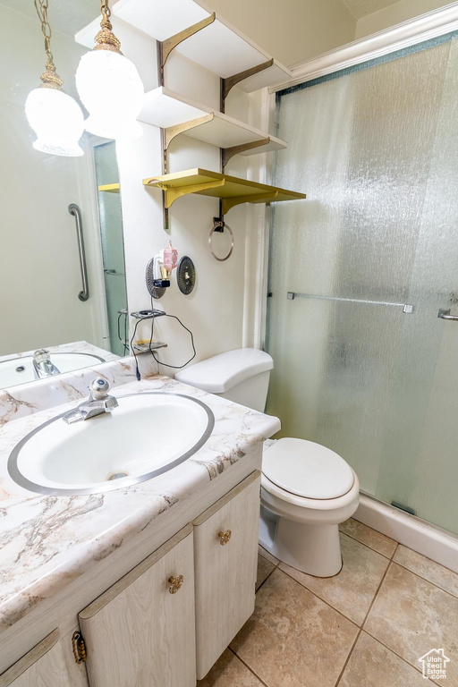 Full bathroom with a stall shower, vanity, toilet, and tile patterned floors