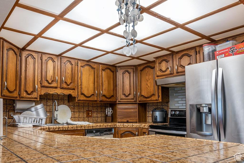 Kitchen with a sink, brown cabinetry, stainless steel appliances, tasteful backsplash, and under cabinet range hood