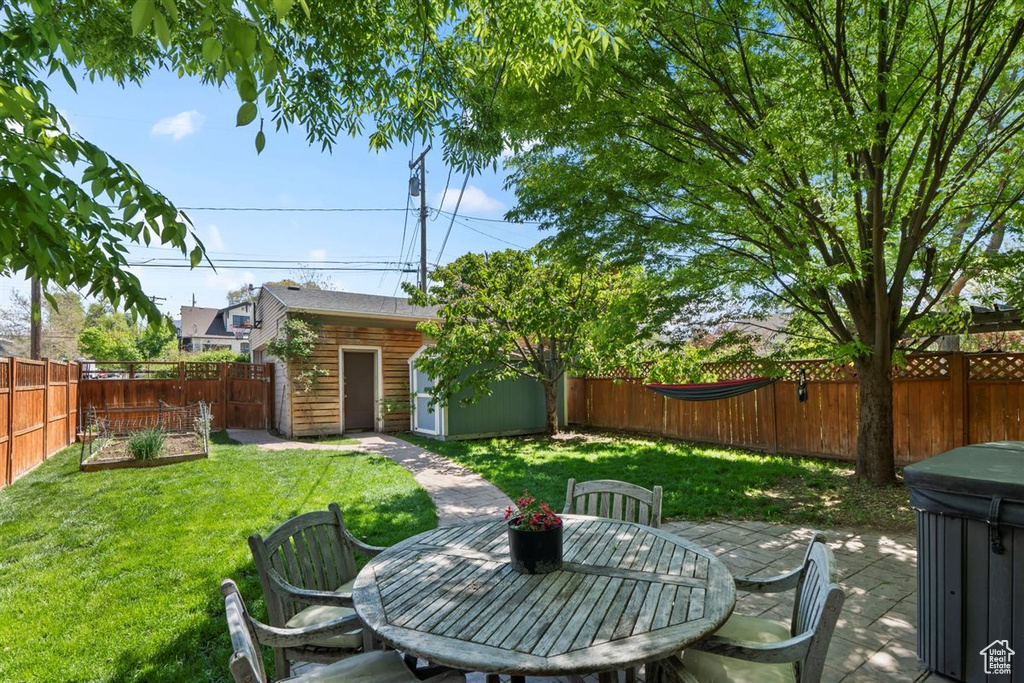 View of yard with a patio, a fenced backyard, and an outbuilding